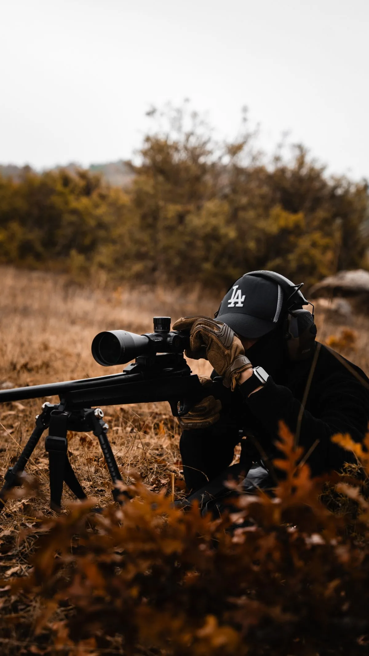 How to read wind for long range shooting: a shooter prone behind a scoped bolt rifle reading the wind in an open field